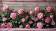   A wooden bench holds a bouquet of pink roses before a green-leafed wooden wall