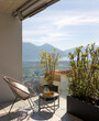 Large terrace of a house in Switzerland with a view of Lake Maggiore. Sunny day and a cosy armchair with cushion.