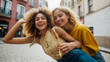 Two young multiracial women having fun on city street outdoors - Mixed race female friends enjoying a holiday day out together - Happy lifestyle, youth and young females concept