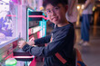Asian boy at one of the mall stores, playing Claw Game.