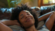 © Arcane Imaginarium - A young happy black woman lying back on a sofa relaxing
