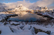 schneebedeckter Berg spiegelt sich in der Bucht bei Reine, Lofoten