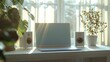 Home office setup with laptop and speakers on a desk by a sunny window with plants.