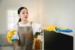 Young housewife is wiping dust off the TV with a microfiber cloth in the living room. Housekeeping concept