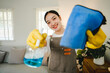 Young female housekeeper holds cleaning supplies in the house