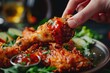 Captivating close-up shot of a person's hands dipping a crispy fried chicken leg into tangy sauce