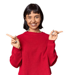 Wall Mural - Young Hispanic woman with short black hair in studio pointing to different copy spaces, choosing one of them, showing with finger.