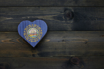 Wall Mural - wooden heart with national flag of new hampshire state on the wooden background.
