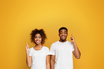 Wall Mural - Cheerful man and woman point index fingers up