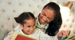 © peopleimages.com - Reading, mother and daughter in bedroom with book, teaching and happy learning time in family home. Knowledge, fantasy and storytelling, mom and child relax on bed together with love, care and story.