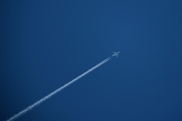 Wall Mural - Airplane in the blue sky with contrails.