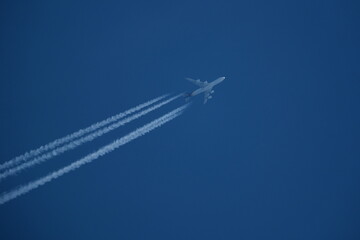 Wall Mural - Airplane in the blue sky with contrails.