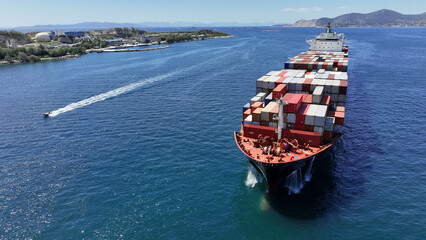 Wall Mural - Aerial drone photo of huge fully loaded container tanker ship carrying truck size colourful containers in deep blue sea near Mediterranean terminal port