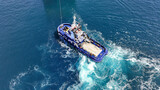 Fototapeta Paryż - Aerial drone top down photo of industrial tug assisting boat cruising in deep blue Mediterranean sea