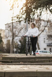 Fototapeta  - Woman Walking With Bicycle Down Stone Steps in Urban Park