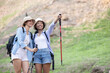 Two female friends pointing to the  view while trekking on the forest path