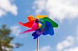 ecology, environment and sustainable energy concept - close up of multicolored pinwheel over blue sky
