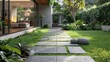 A path of gray square tiles on the grass in a garden outside the house. Path made of tiles with a touch of sophistication and refinement in a harmonious combination.