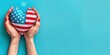 A pair of hands holding an American flag heart-shaped balloon, rising against a clear blue backdrop