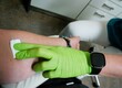 Ärztin mit grünen medizinischen Gummihandschuh drückt weißen Wattepad auf Arm von Patientin nach Blutabnahme in Arztpraxis