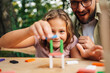 © Zamrznuti tonovi - Close up of a girl making tower of wooden blocks while dad is watching