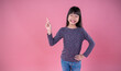 Portrait of young beautiful little asian girl hand point up isolated on pink background wall with copy space. Education for toddler or preschool, childhood lifestyle back to school concept