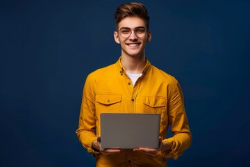 Photo portrait of nice young male hold netbook specs smm manager dressed stylish yellow garment isolated on dark blue color background