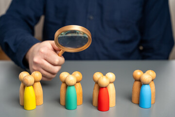 The concept of market segmentation. Target audience, customer care. Market group of buyers. Customer relationship management. Businessman looking through a magnifying glass at figurines of people