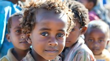 Children Of Eritrea, A Close-up Of A Young Child With Curly Hair And Engaging Eyes Surrounded By Other Children In Soft Focus Offering A Glimpse Of Life In A Vibrant Community 