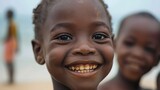 Fototapeta  - children of mozambique, Close-up of a joyful young child with a broad, sparkling smile on a blurred beach background. 