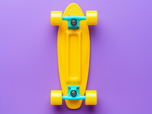 Vibrant Violet Skateboard Contrasts Against A Pastel Backdrop With Yellow Wheels