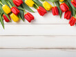 Rustic white wood serves as the canvas for a vibrant bouquet of tulips, daffodils, and eucalyptus