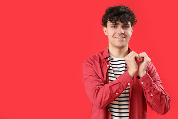 Poster - Handsome young man making heart with his hands on red background