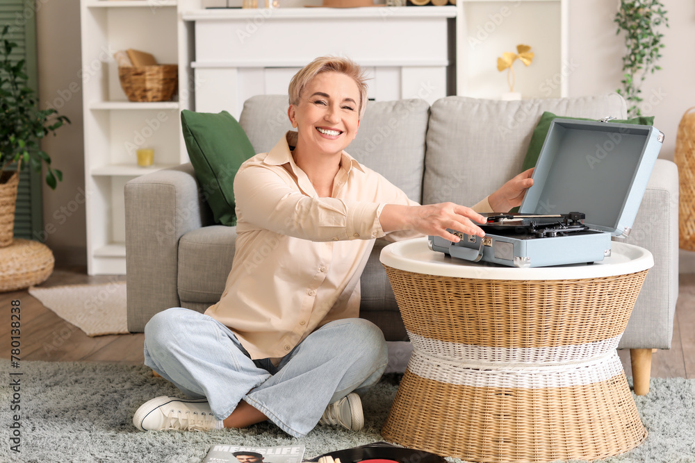 Mature woman with record player sitting at home