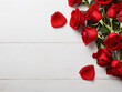 A top-view flat lay exhibits red roses on a white wooden background, offering free space for text