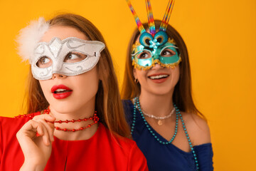 Sticker - Beautiful young women in carnival masks on yellow background