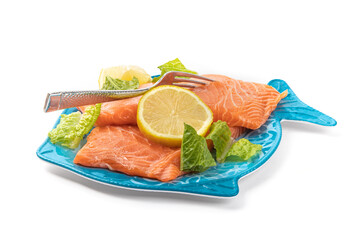 Wall Mural - Pieces of Salmon filet on a blue fish shaped plate with lemon slice and garnish ready to be cooked isolated on white

