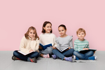 Canvas Print - Little children reading books while sitting on floor near pink wall