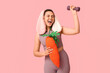 © Pixel-Shot - Happy female fitness coach in bunny ears with toy carrot and dumbbell on pink background. Easter celebration