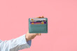 Female hand with credit card holder on pink background