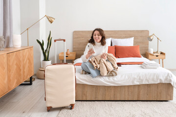 Poster - Female tourist using mobile phone on bed in hotel room