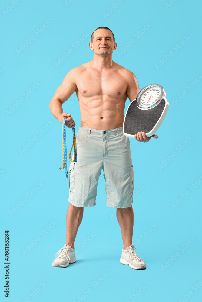 Male bodybuilder with measuring tapes and weight scales on blue background