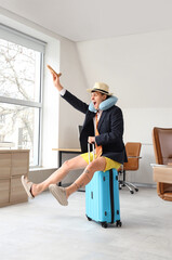 Canvas Print - Young businessman with wooden airplane and suitcase ready for summer vacation in office