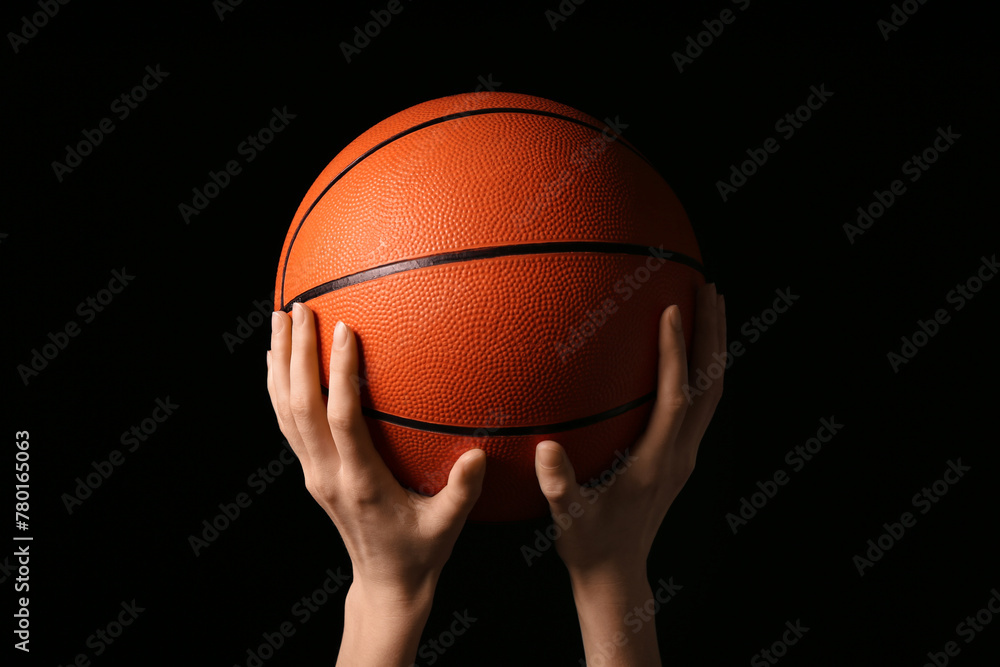 Young basketball player with ball on black background