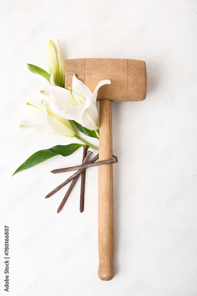 Wooden hammer, lilies and nails on white background