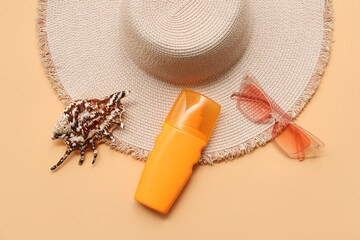 Bottle of sunscreen cream, seashell, sunglasses and hat on orange background