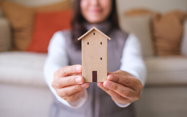 Wall Mural - Closeup image of a young woman holding and showing a wooden house model