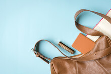 Woman Handbag With Phone, Lipstick And Notepad. On Blue Background, Copy Space.