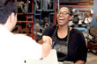 © Stella - Happy African American woman staff with apron making handshake with customer after completing business deal at auto spare parts store warehouse with secondhand engine parts. Owner offer deal to buyer.