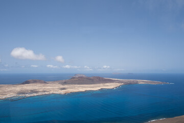 Wall Mural - Views of the island of La Graciosa from the viewpoint of El Rio. Turquoise ocean. Blue sky with big white clouds. Caleta de Sebo. Town. volcanoes. Lanzarote, Canary Islands, Spain